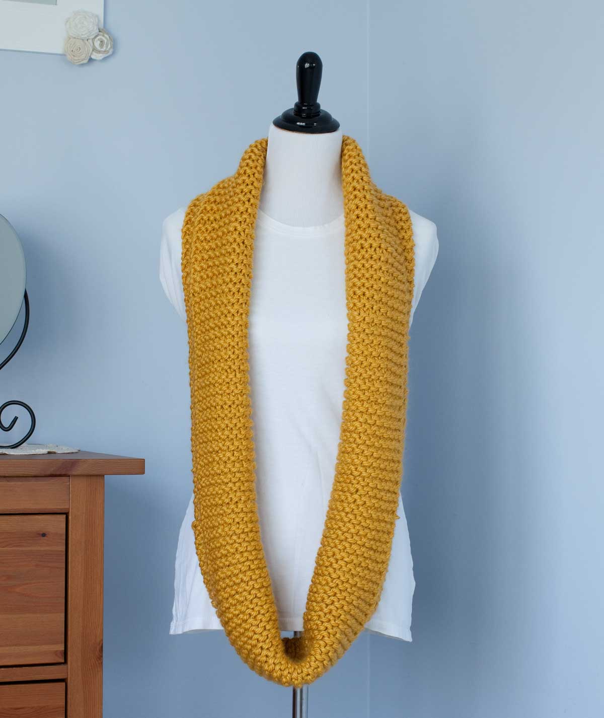 Mustard yellow scarf folded in half width wise and hung around a dress-makers dummy.